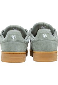 Grå sued sneakers med gummisåler, med polstrede krager og hvite logo-detaljer på baksiden. Teksturert materiale gir godt grep.