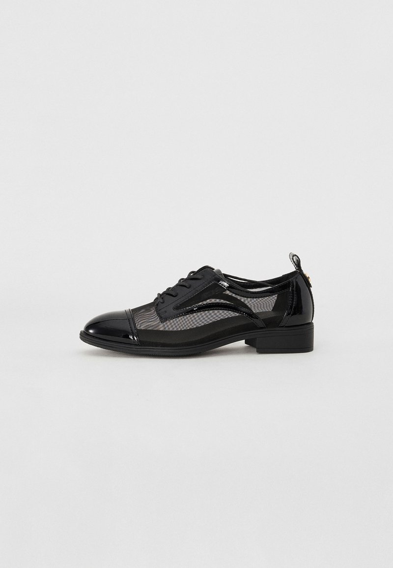 Chaussure Oxford noire à petit talon avec bout et talon en cuir verni brillant, côtés en mesh et laçage à l'avant, sur fond blanc.