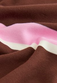 Tissu tricoté doux avec des rayures horizontales marron, rose et blanc, présenté avec de délicats plis et détails de texture.