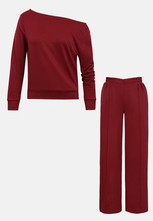 Haut bordeaux à manches longues avec encolure asymétrique décolletée, associé à un pantalon large taille haute assorti.