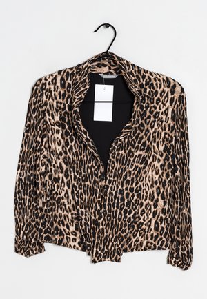 Blouse à manches longues imprimée léopard avec col, suspendue sur un cintre noir, avec une étiquette de prix blanche à l’intérieur de l’encolure.
