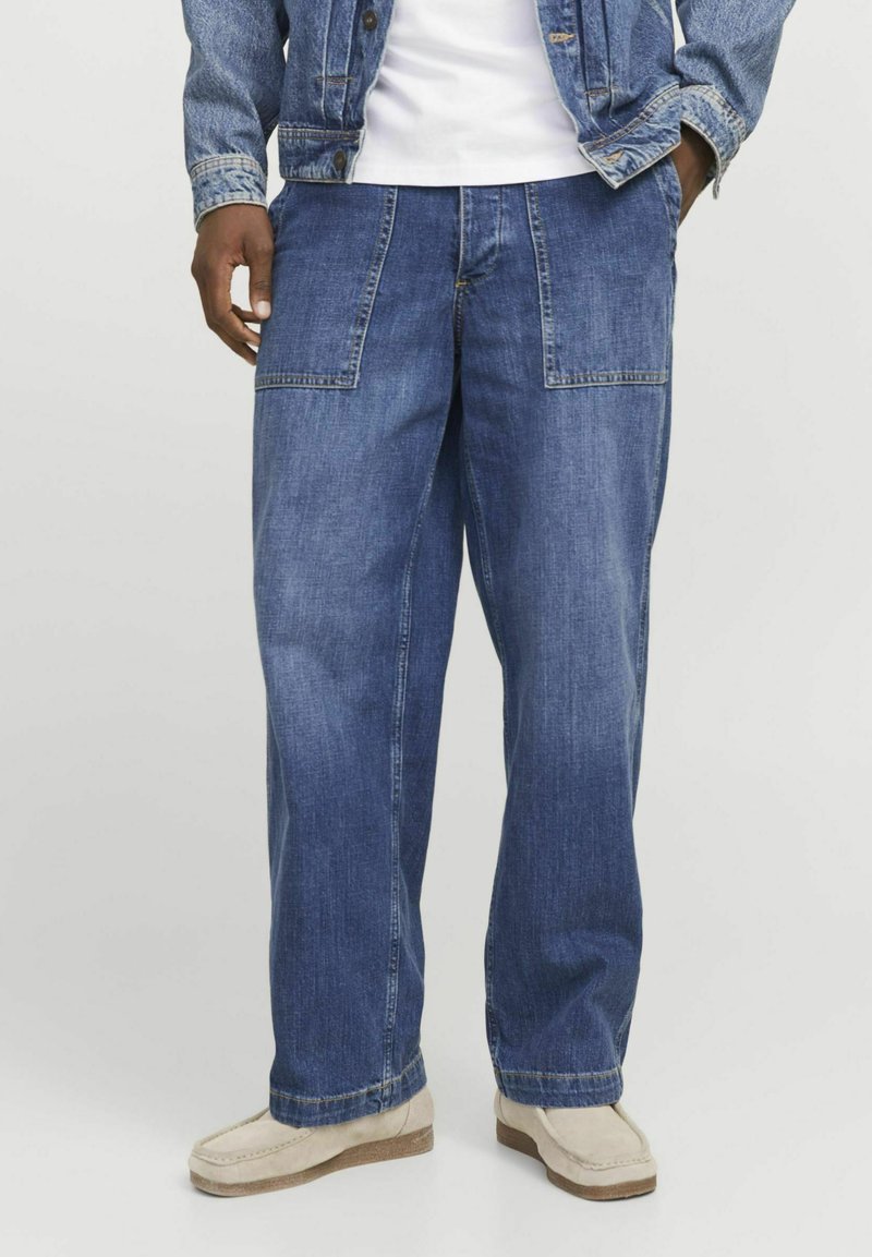 Jeans de mezclilla azul con un corte relajado, que cuentan con grandes bolsillos frontales, costuras visibles y una textura ligeramente desgastada.