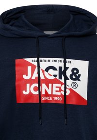 Sudadera navy con un gráfico en el frontal; presenta un logo rojo y blanco con el texto “JACK & JONES” y “SINCE 1990.” Cierre con cordón.