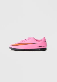 Rózsaszín alacsony szárú Nike Mercurial focicipő fekete talppal és narancs színű swoosh logóval, oldalnézet, sima világos háttéren.