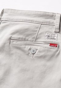Graue Baumwollhosen mit einer Gesäßtasche mit Knopfverschluss, Levi's Markenetikett und dezenten Stickdetails.