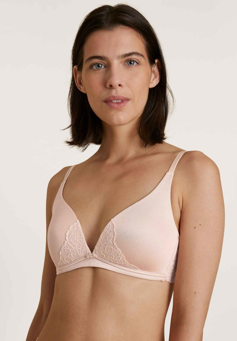 Lace-trimmed, soft pink bra with a triangular shape and adjustable straps, featuring a smooth texture and delicate detailing at the edges.