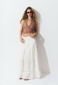 Strap halter crop top in red and orange stripes, paired with a white tiered maxi skirt featuring a smocked waistband and lace trim.