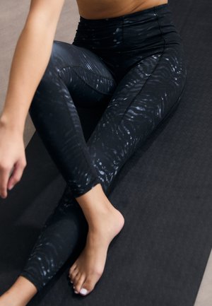 Leggings negre cu un model texturat, asemănător unor unde. Design cu talie înaltă, realizate dintr-un material elastic, potrivite pentru îmbrăcăminte sport.