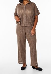 Brązowy dwuczęściowy zestaw szydełkowy z krótkim rękawem, z button-up topem i luźnymi spodniami, ozdobionymi skomplikowanymi diamentowymi wzorami oraz teksturowanym materiałem.