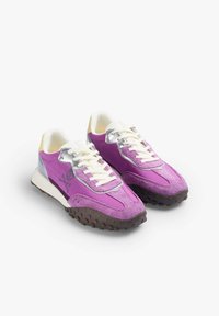 Baskets violettes en suède et cuir, avec des accents argentés, des lacets blancs et des semelles brunes texturées présentant une traction marquée.