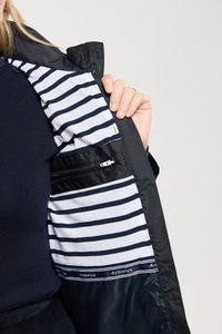 Giacca nera con un interno a righe navy e bianche foderato. Presenta una tasca con zip all'interno. Il materiale sembra liscio e resistente.