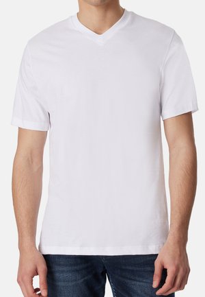 Male wearing plain white short-sleeve V-neck t-shirt and blue jeans, shown from shoulders to hips, standing against a white background.