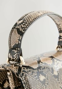Håndtaske med slangeskindsudseende, der har en sort læderhank, gyldne hardwaredetaljer og et struktureret design. Teksturbelægning er synlig.