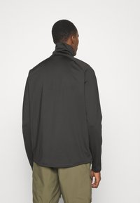 Suéter negro de manga larga con cuello alto, hecho de una tela lisa. Presenta un corte relajado y costuras planas para mayor comodidad.