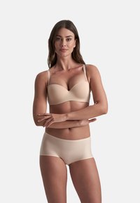 Beige gepolsterde bh met verstelbare bandjes en bijpassende bikini-stijl onderkant. Gladde textuur met minimale naden voor een naadloze uitstraling.