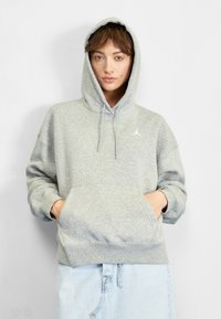 Szürke kapucnis pulcsi állítható zsinórokkal, nagy elülső zsebbel és a mellkason fehér Jumpman logóval. Puha tapintású és kényelmes szabású.