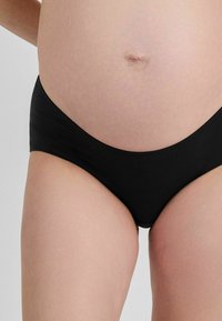 Černé materské kalhotky vyrobené z hladkého, pružného materiálu. Vysoký pas, bezešvé okraje a střední pokrytí vhodné pro těhotenství.
