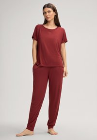 Bordeaux loungewear set, bestaande uit een T-shirt met korte mouwen en losse broek, gemaakt van zacht materiaal met een subtiel boomontwerp.