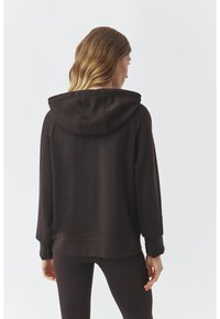Sudadera con capucha de color marrón oscuro, fabricada en un tejido suave, con un corte relajado, puños acanalados y un bolsillo canguro en la parte delantera.