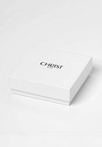 Weiße rechteckige Box mit schwarzem Text "CHRIST seit 1863" zentriert auf dem Deckel, auf einer weißen Fläche platziert.