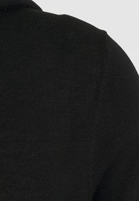 Maglione nero a maglia con una texture liscia, caratterizzato da un colletto a girocollo e delicate rifiniture a coste lungo i bordi.