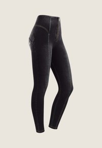 Pantaloni neri a vita alta con cerniera, caratterizzati da cuciture verdi a contrasto e una tasca posteriore, realizzati in un materiale simile al denim.
