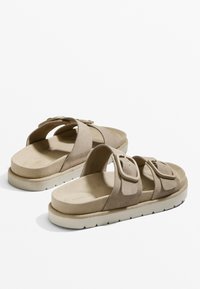 Beige velúr szandálok két széles pánttal, állítható csatokkal, kontúros talpbéléssel és texturált fehér gumitalppal.