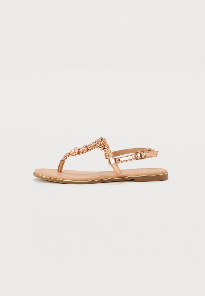 Bronze flat sandals with a toe post design, embellished with beads and a buckle ankle strap. Smooth texture with a flat sole.