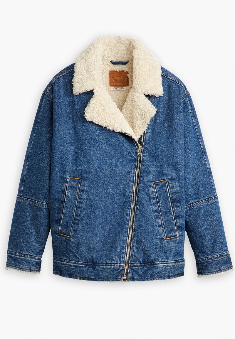 Veste en denim avec un col en sherpa crème en peluche, fermeture éclair, deux poches latérales et une texture bleue décolorée. Étiquette en cuir à l'intérieur.