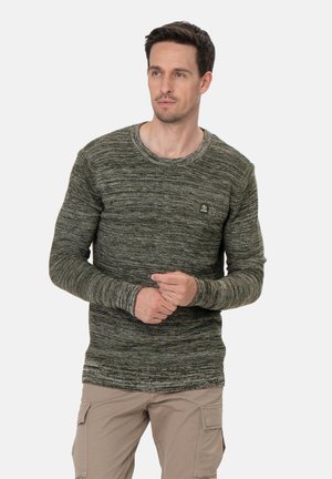 Suéter verde de punto con cuello redondo, tejido texturizado y un pequeño parche de logo en el pecho. Manga larga, estilo ajustado.