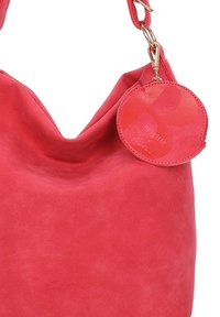 Sac à bandoulière en cuir rouge avec une pochette à pièces ronde et amovible attachée à la sangle par un fermoir en or.