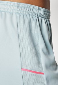 Lichtblauwe sportkorte broek met een gestructureerd zijpaneel, elastische tailleband en een roze accentstreep. Gemaakt van ademende stof.