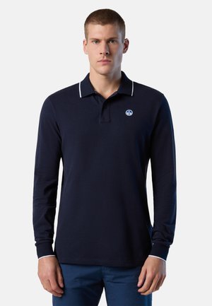 Polo a maniche lunghe blu navy in cotone, con colletto bianco a contrasto e un piccolo logo rotondo in alto a sinistra.