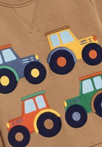 Ruskopartainen huppari, jossa on värikkäitä brodeerattuja traktoreita sinisissä, keltaisissa, oransseissa ja vihreissä sävyissä, jokaisessa on erottuvat renkaat ja ikkunat.