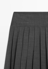 Jupe plissée gris foncé avec une large ceinture et deux poches horizontales fendue à l'avant.