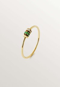 Anillo de oro con una banda estrecha y un racimo de dos piedras verdes y dos piedras transparentes engastadas en un bisel decorativo.