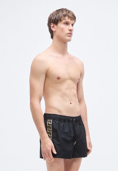 Μαύρα μαγιό σορτς με χρυσό γεωμετρικό σχέδιο, με ελαστική μέση και κορδόνι. Λείο, ελαφρύ υλικό.