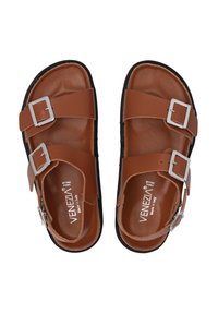 Braune Ledersandalen mit zwei breiten Riemen, silbernen Schnallen und einer schwarzen Gummisohle, gekennzeichnet durch eine glatte Oberflächenstruktur und minimalistisches Design.