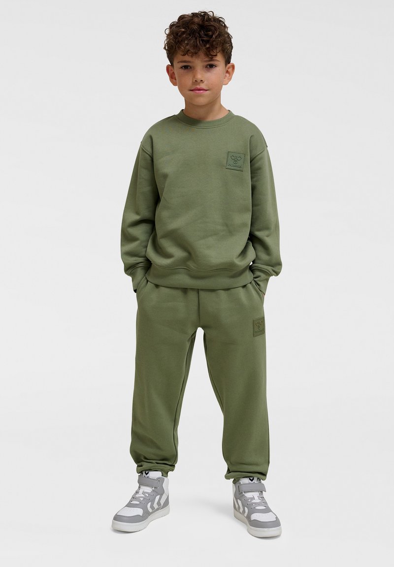 Felpa verde oliva e pantaloni abbinati realizzati in morbido tessuto, con polsini a costine e una piccola toppa con logo sul petto e sulla coscia.