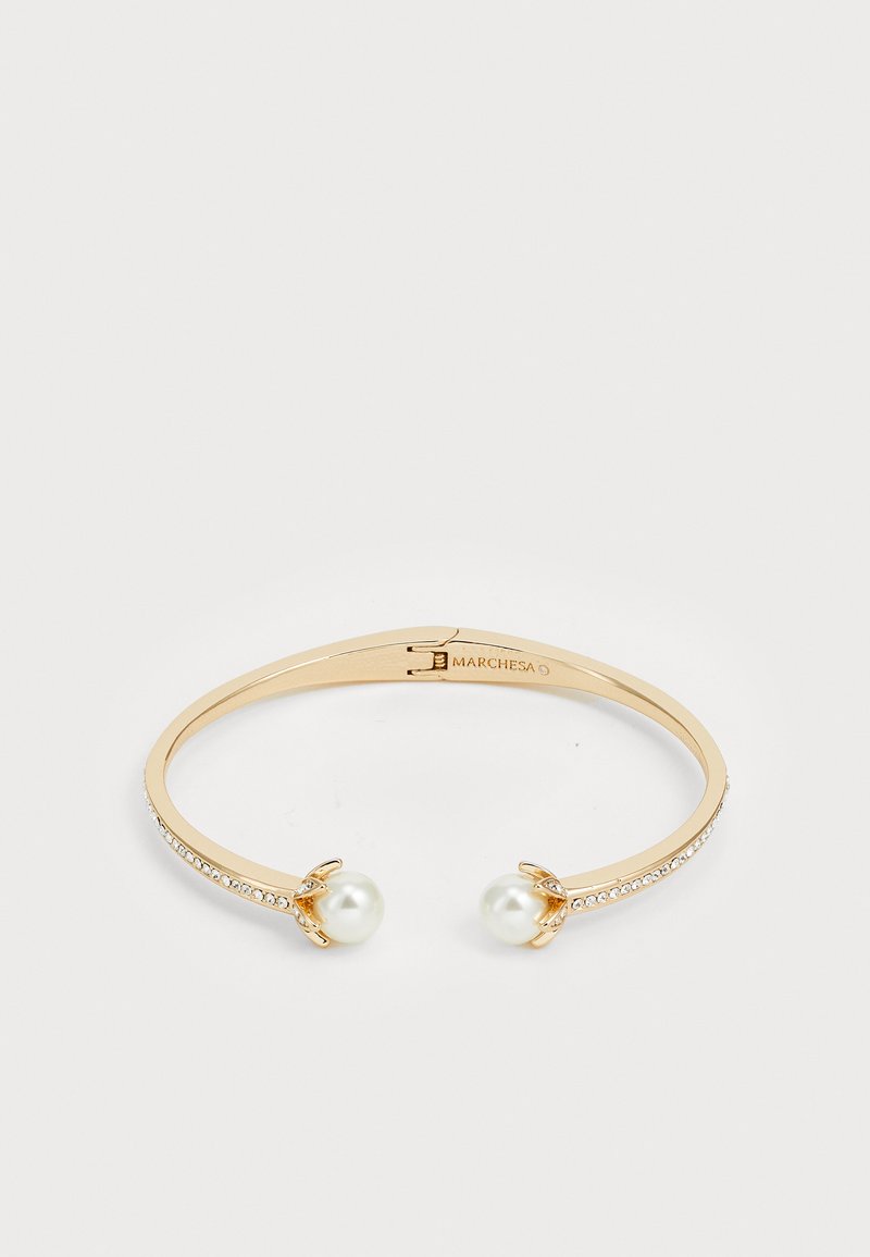 Auksinės spalvos apyrankė su dviem baltais perlais ir maža skaidrių akmenukų eile vienoje pusėje, elegantiška forma su lygiu paviršiumi.