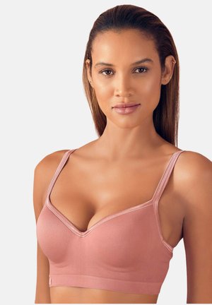 Woman with straight hair wearing a pink wireless bra with thin straps, facing forward against a plain light background.