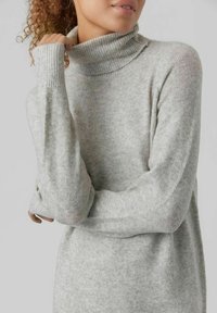 Maglione a collo alto grigio chiaro realizzato in materiale morbido e testurizzato, con maniche lunghe con polsini a costine e colletto ripiegato.