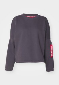 Tmavě �šedá mikina s dlouhými rukávy, kulatým výstřihem, elastickými manžetami a kapsou na rukáv s malým červeným štítkem s bílým nápisem.