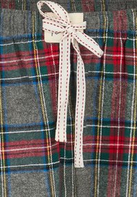 Geruite loungeschaar met een grijze basis en rood, groen en blauw ruitpatroon. Vastgemaakt met een crèmekleurig lintaccent en voorzien van stikdetails.