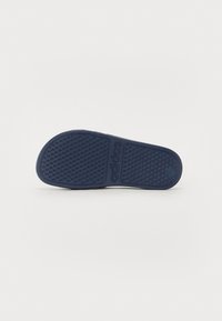 Rubber shoe sole in navy blue, featuring textured grip patterns and embossed branding. Smooth edges and contoured shape for comfort.
