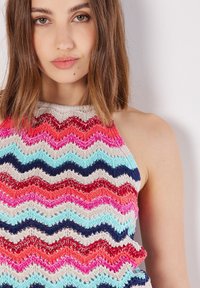 Top halter de punto con un patrón ondulado en rosa, rojo, azul y crema, elaborado con hilo texturizado y un diseño de tejido abierto.
