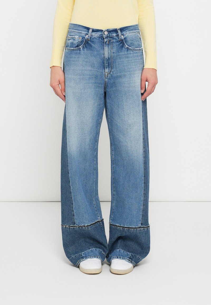 Φαρδιά τζιν παντελόνια σε ανοιχτό γαλάζιο χρώμα με εφέ ξεθωριάσματος, διαθέτουν υψηλή μέση, μπροστινές τσέπες και αντίθετες ραφές στο τελείωμα. Συνδυασμένα με λευκά παπούτσια.