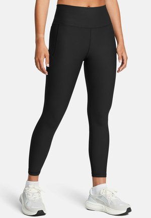 Sorte ribbede leggings med høj talje, der har sidelommer og en tætsiddende silhuet. Bæres med hvide sportssko.