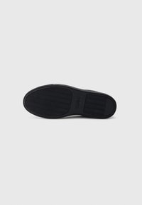Black rubber shoe sole with textured grooves and logo. Features a smooth, rounded shape and flat design for consistent surface contact.