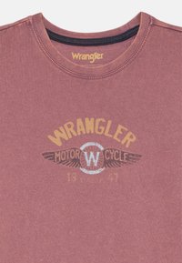 Karmínové bavlněné tričko s kulatým výstřihem, se starožitným potiskem Wrangler Motorcycle v žluté a stříbrné barvě s křídly.